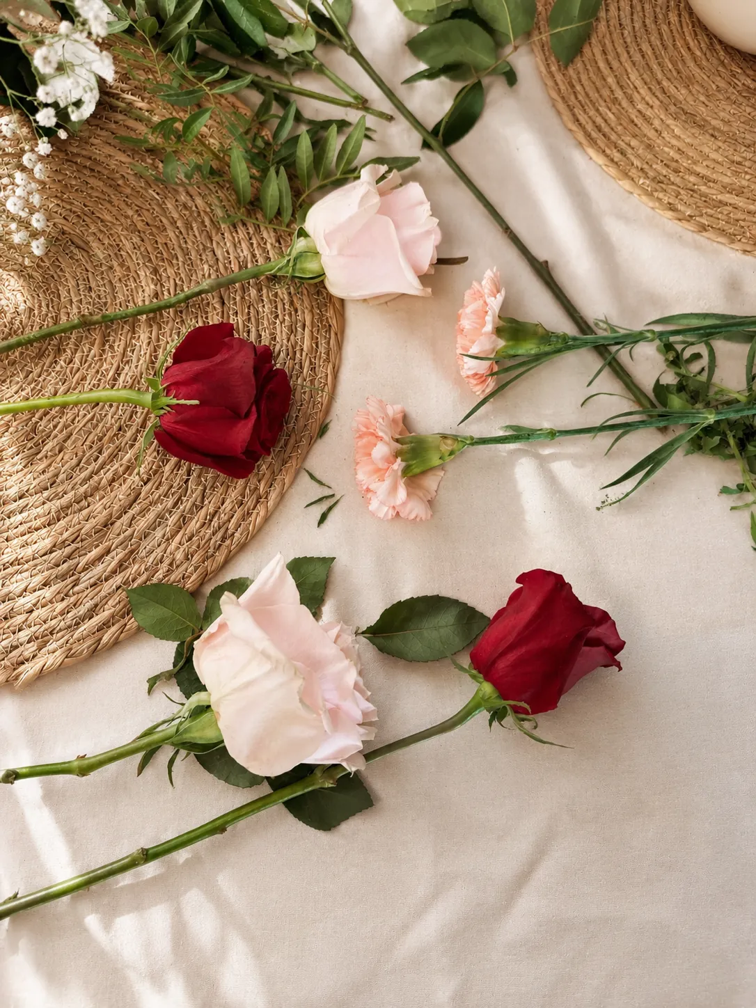 Rosas granate y rosadas con claveles, flores frescas de temporada sobre la mesa de trabajo de la floristería